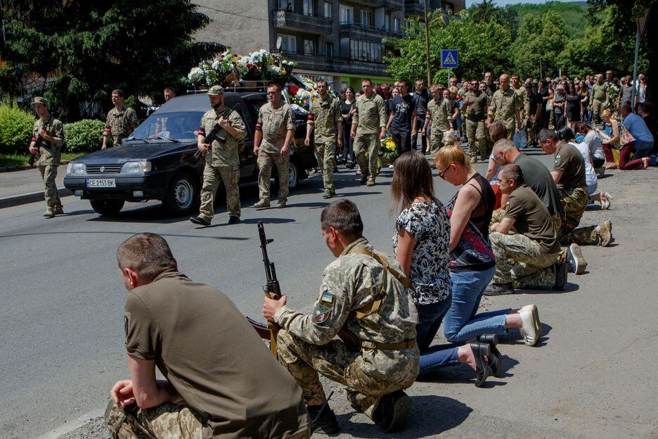 Residentes de Perechyn se ajoelham para a passagem do cortejo fúnebre do soldado ucraniano Vasyl Herych, de 31 anos,  morto pelas forças russas 